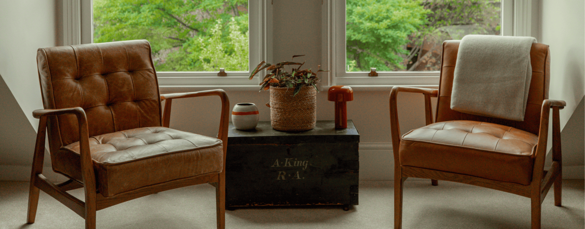 Cozy Victorian-style living room with two armchairs and a window view of greenery.