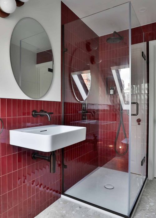 Modern Victorian bathroom with red tiles and glass shower enclosure.
