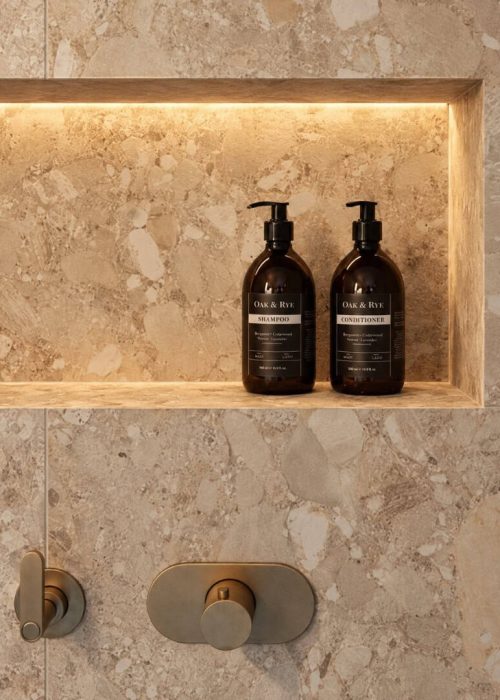 Elegant bathroom shelf with black shampoo and conditioner bottles in a modern shower.