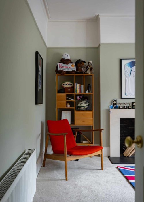 Cozy reading corner with red armchair and bookshelf in a Victorian home.
