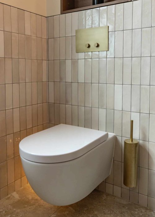 Modern wall-mounted toilet with beige tiled wall in Victorian bathroom.