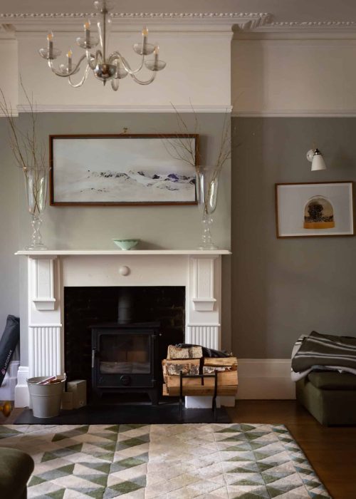 Elegant Victorian living room with fireplace, artwork, and decorative vases.