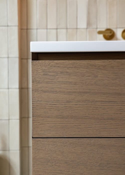 Close-up of a wooden bathroom vanity with a white countertop in a Victorian-style bathroom.