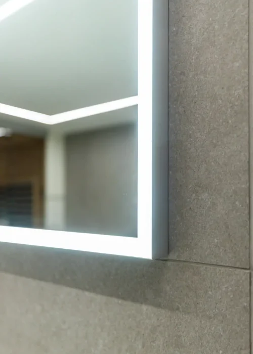 Close-up of modern bathroom mirror with LED lighting and textured wall.