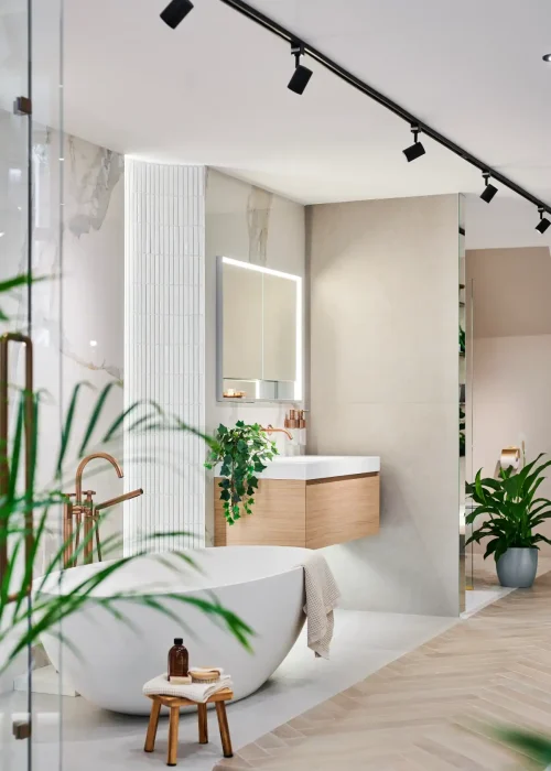 Modern bathroom with freestanding bathtub, wooden vanity, and green plants.