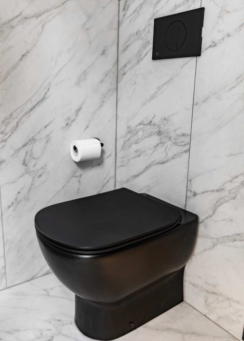 Modern black toilet with marble wall background in bathroom.