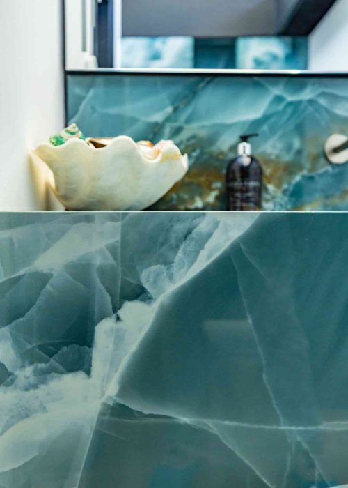 Elegant green marble bathroom with shell-shaped decor and soap dispenser.