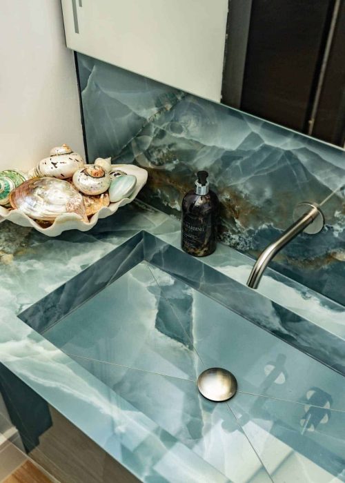 Elegant blue marble bathroom sink with seashell decor and modern fixtures.