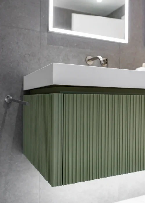 Modern green bathroom vanity with white sink and mirror in contemporary bathroom setting.