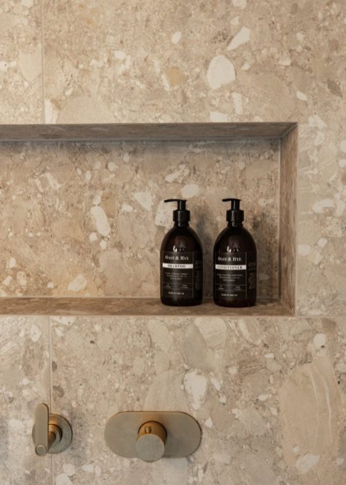 Two black bathroom bottles on a stone shelf in a Victorian-style bathroom.