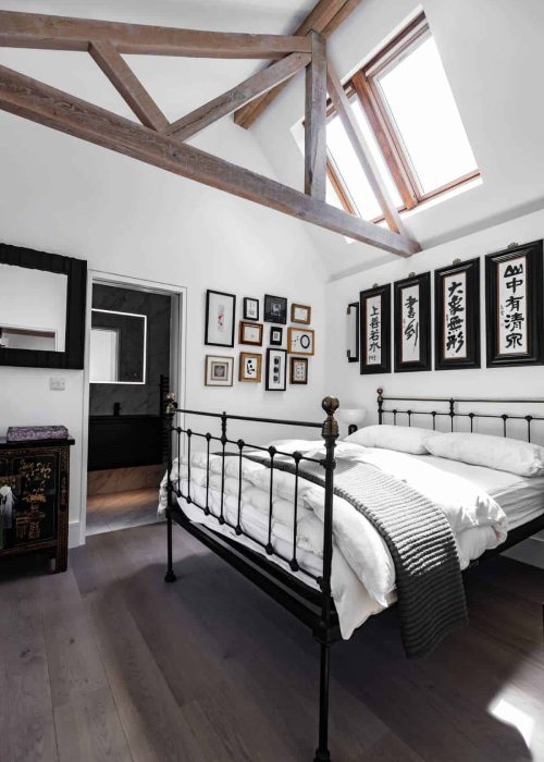 Cozy bedroom with black metal bed and gallery wall of framed art and calligraphy.