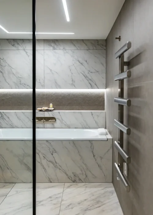 Modern marble bathroom with sleek towel radiator and minimalist design.