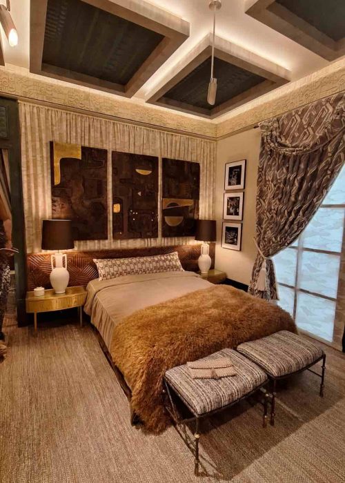 Dark stained coffered ceiling with recessed lighting over a richly layered bedroom at WOW!house 2026 Design Centre Chelsea Harbour