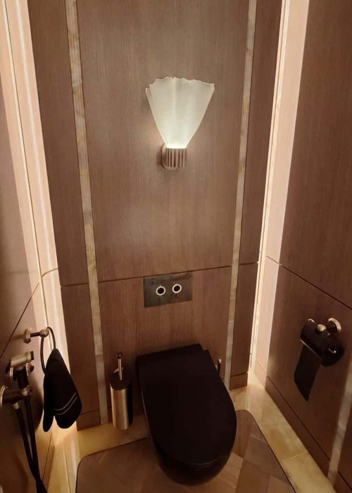 Dark wood panelled WC with fan-shaped wall light at WOW!house 2026, Design Centre Chelsea Harbour.