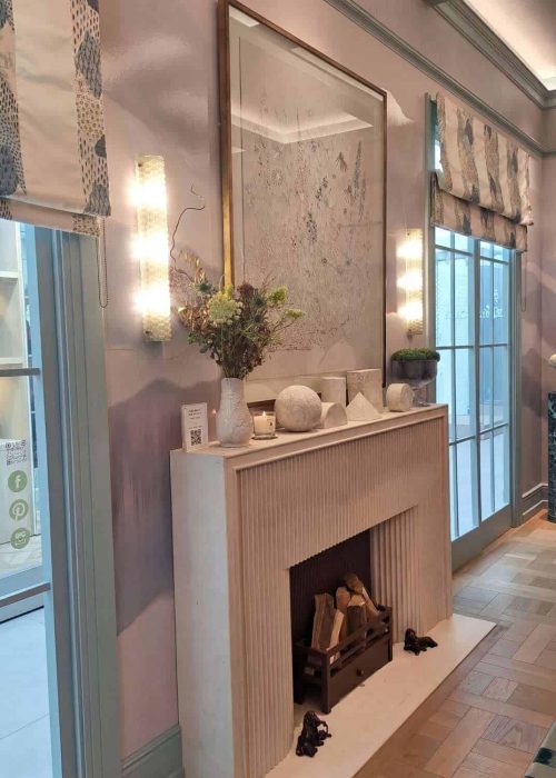 Fluted stone fireplace with brass-framed mirror and textured wall at WOW!house 2026 London.