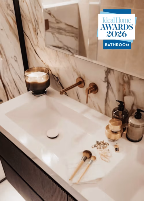 A stylish bathroom sink with a gold faucet and a rectangular mirror reflecting the surroundings.